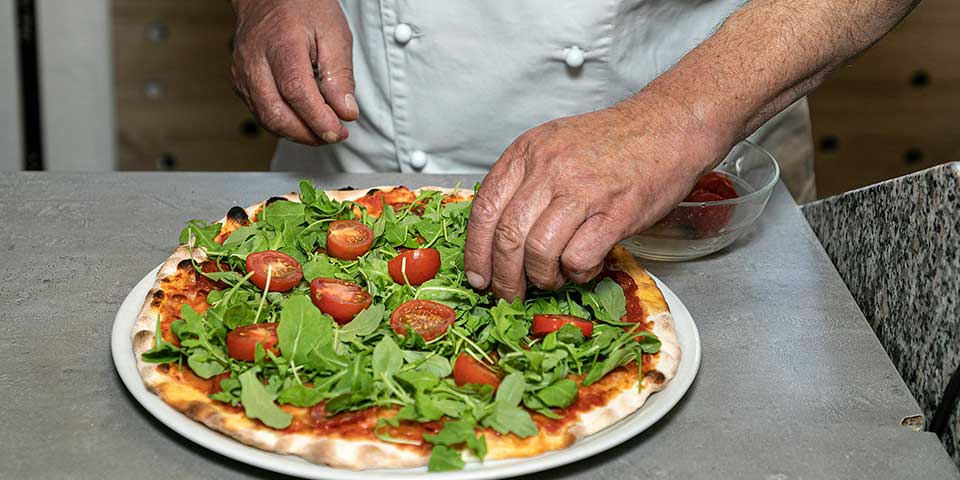 Pizza mit Rucola und frischen Tomaten